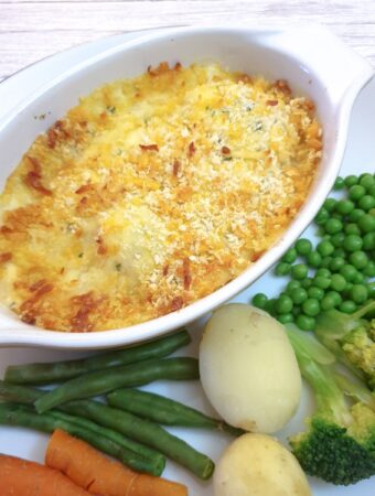 Close up of cod mornay, showing the flaky fish and prawns under the cheese sauce.