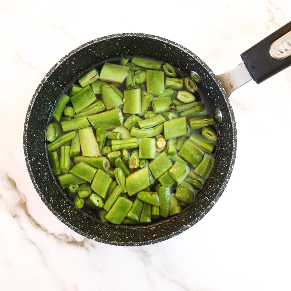 Green beans in a saucepan of water.