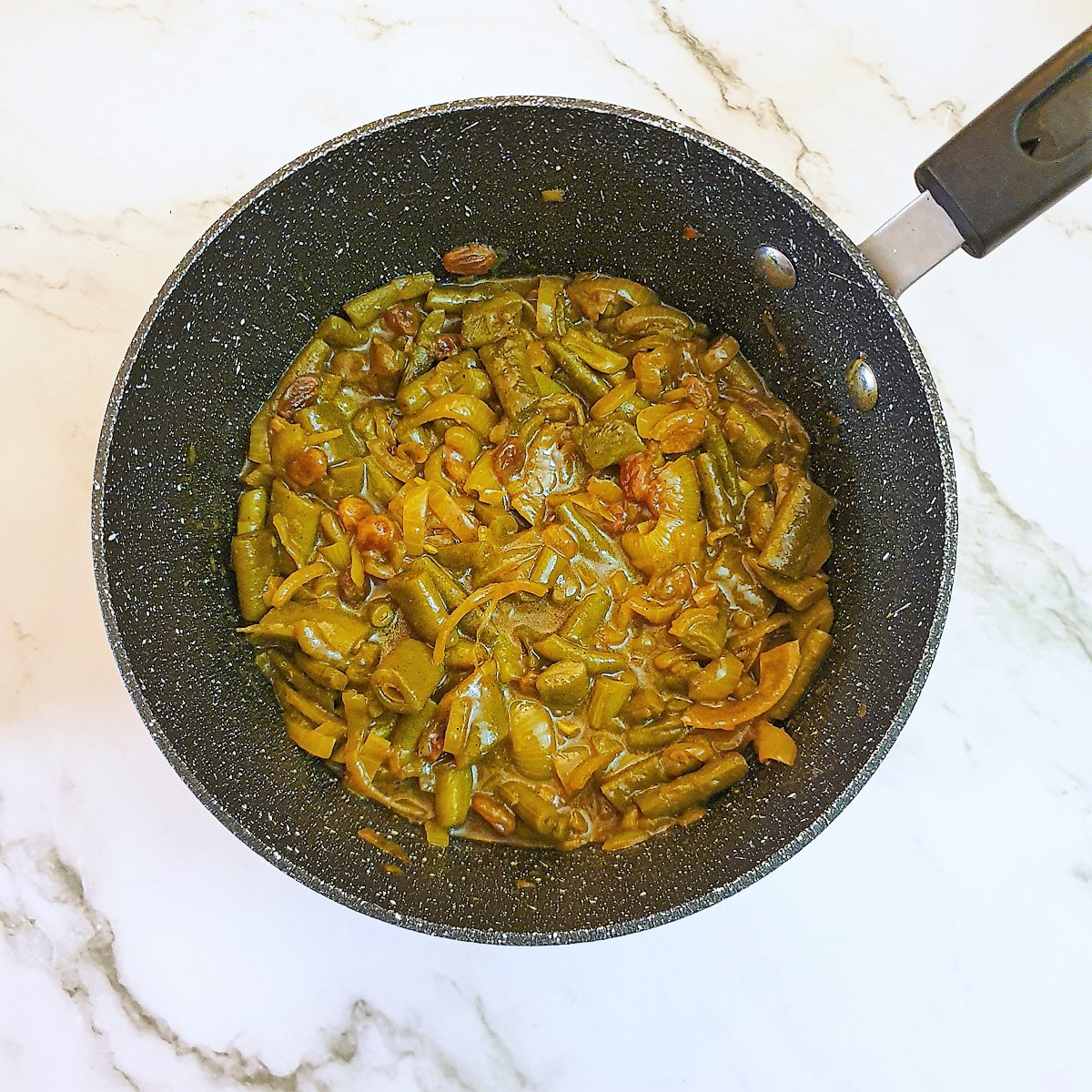 A saucepan containing curried green bean salad.
