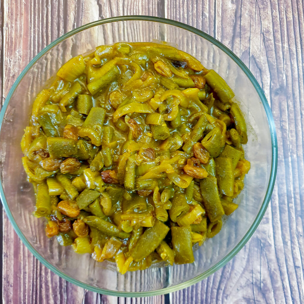 A bowl of curried green beans and onions.