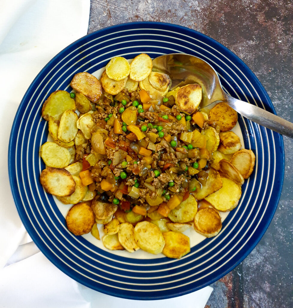 Deconstructed cottage pie in a serving dish with a spoon.