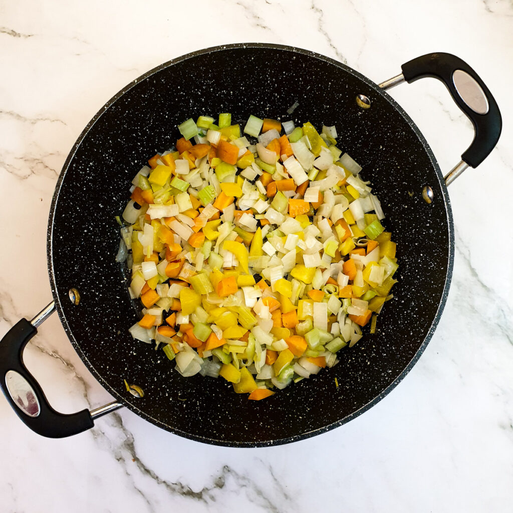 Carrots, onions, leeks, peppers and celery in a frying pan.