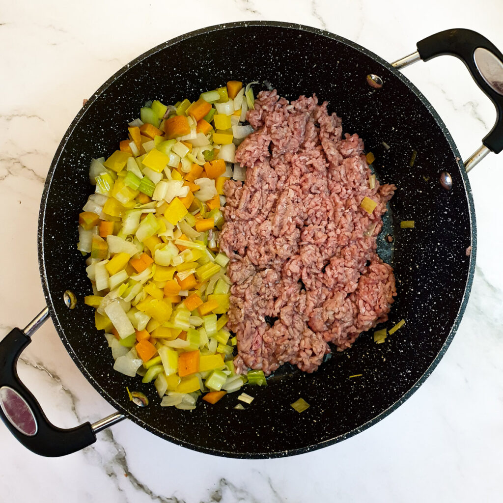 Carrots, onions, leeks, peppers and celery being fried with minced beef.