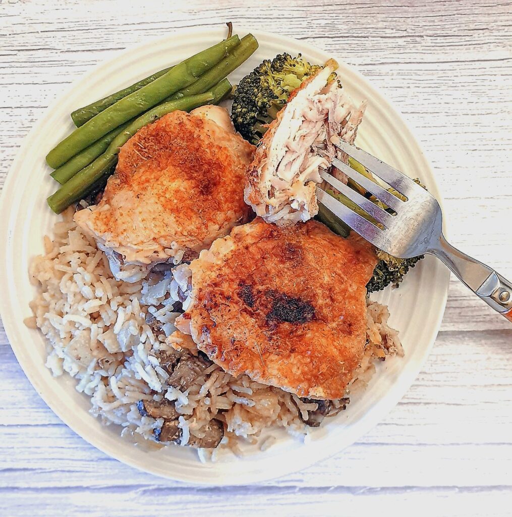 A plate of garlic chicken thighs with rice and vegetables.