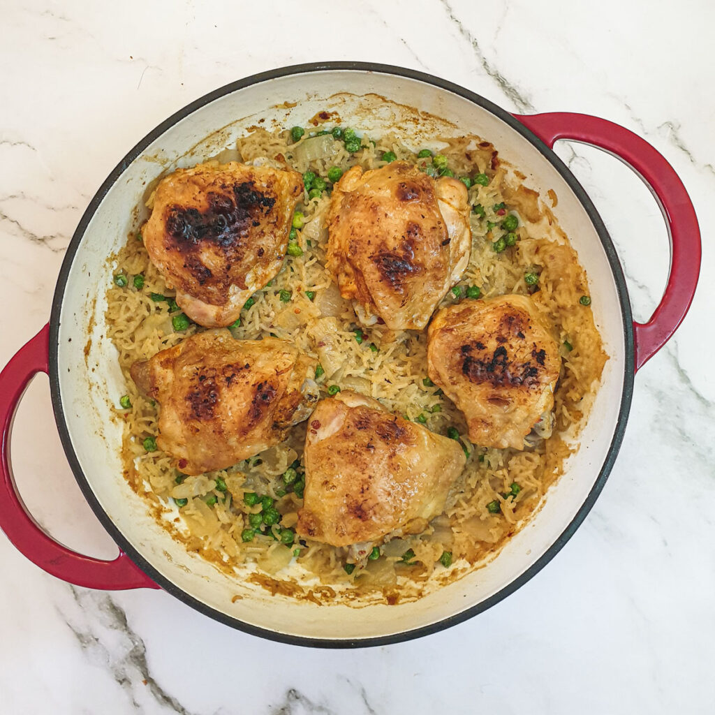 A baking dish with 5 pieces of garlic chicken on a bed of rice.