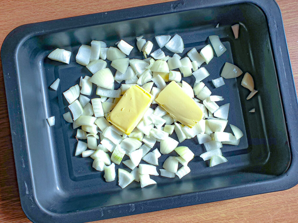 Onions and butter in a roasting pan.