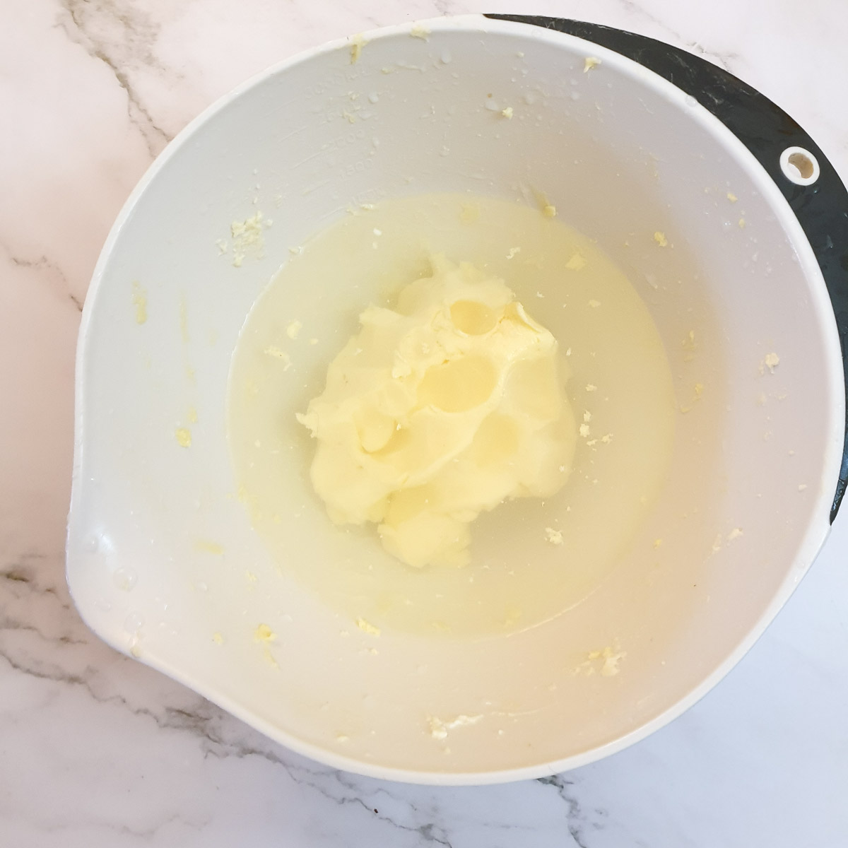 A lump of butter being rinsed in a bowl of cold water.