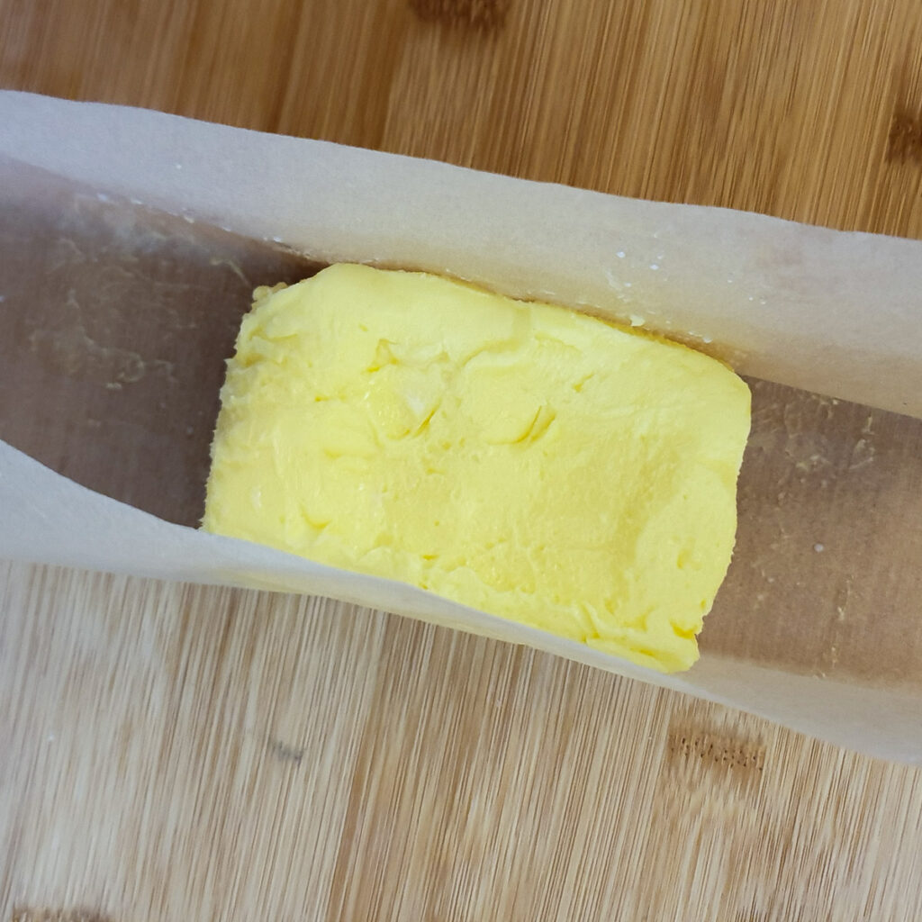 Butter being formed into a brick shape with the help of greaseproof paper.