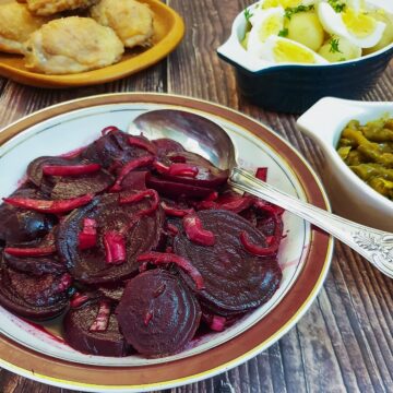 A dish of spicy beetroot salad on a table with other salads.