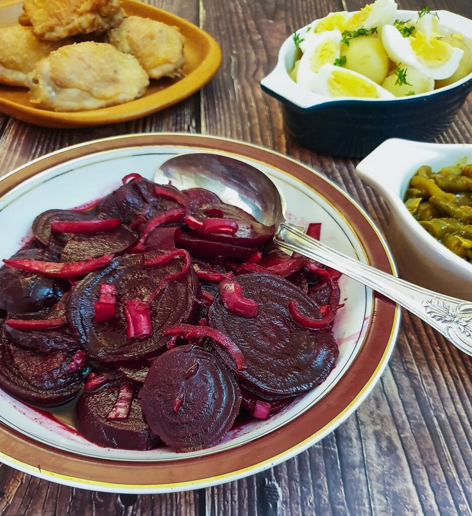 A dish of spicy beetroot salad on a table with other salads.