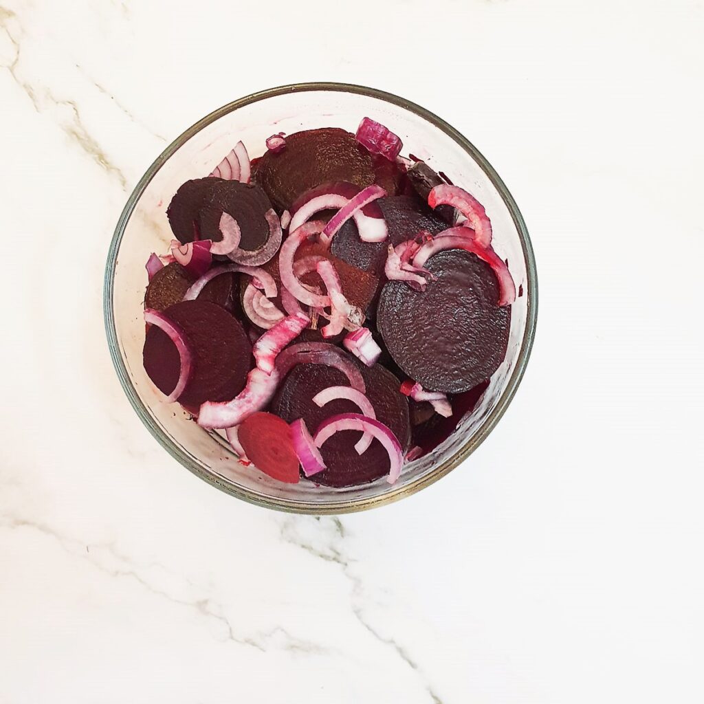 Sliced beetroot and onions in a glass dish.