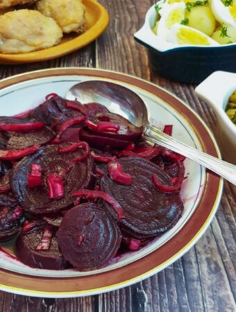 A dish of spicy beetroot salad on a table with other salads.