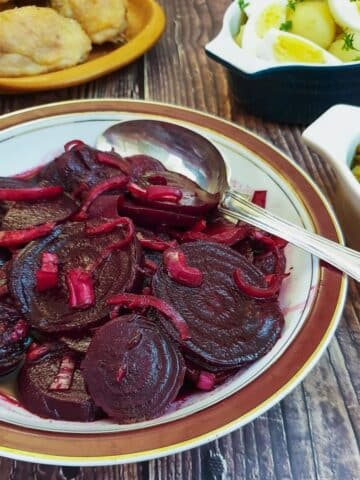 A dish of spicy beetroot salad on a table with other salads.