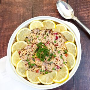 A bowl of tuna noodle pasta garnished with lemon slices.