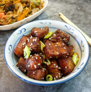 A dish of twice-cooked pork belly garnished with sesame seeds and spring onions.