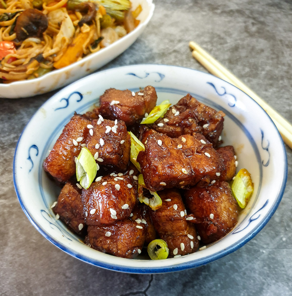 A dish of twice-cooked pork belly garnished with sesame seeds and spring onions.