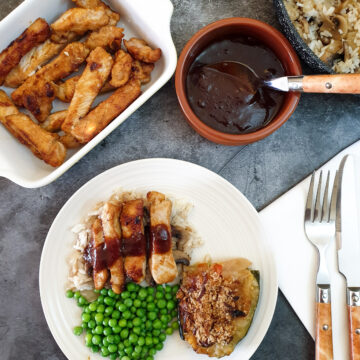 Overhead shot of barbeque pork on a plate next to a bowl of barbeque sauce.