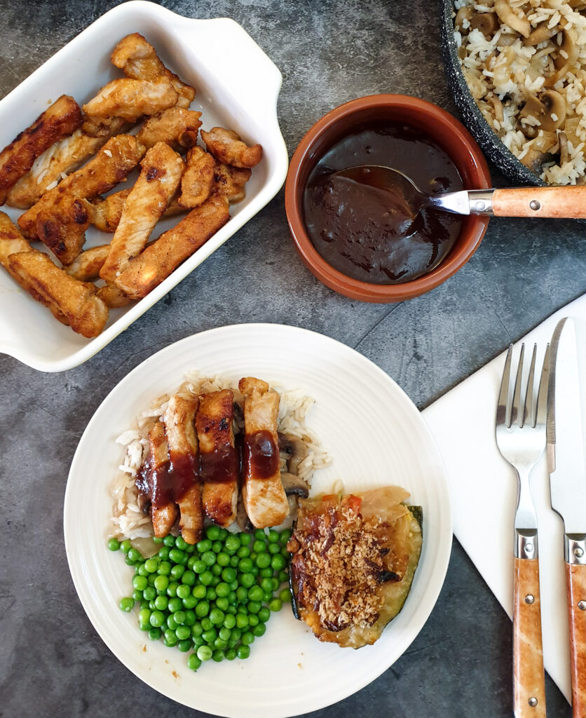 Overhead shot of barbeque pork on a plate next to a bowl of barbeque sauce.