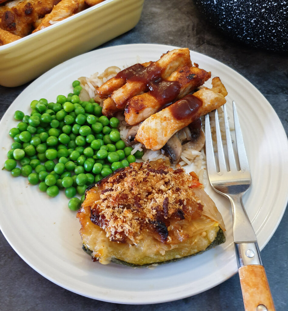 Pork strips on a bed of mushroom rice covered with barbeque sauce, with vegetables.