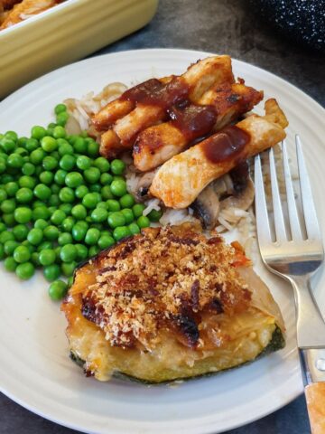 Pork strips on a bed of mushroom rice covered with barbeque sauce, with vegetables.