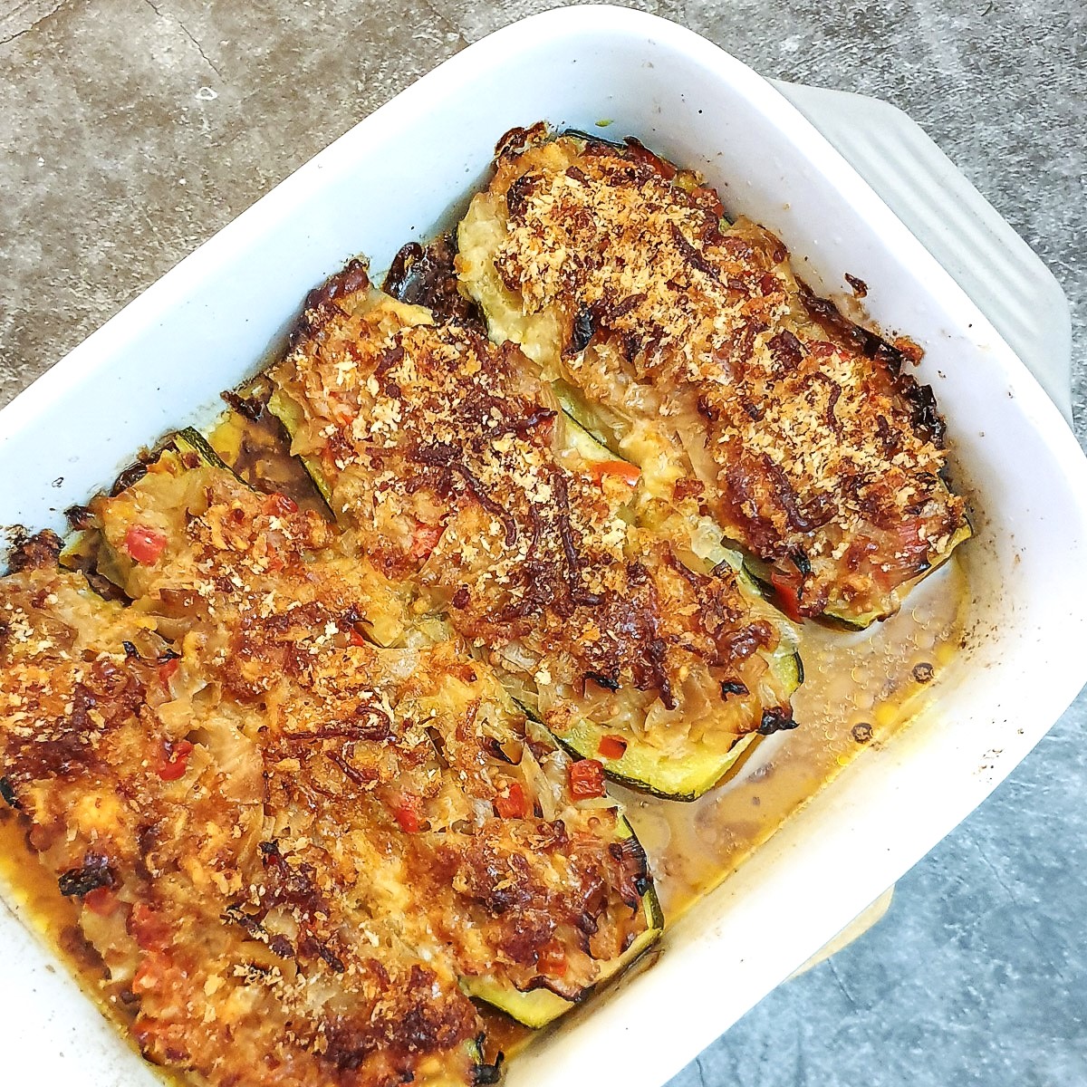 A baking dish containing 4 cabbage-stuffed courgettes.