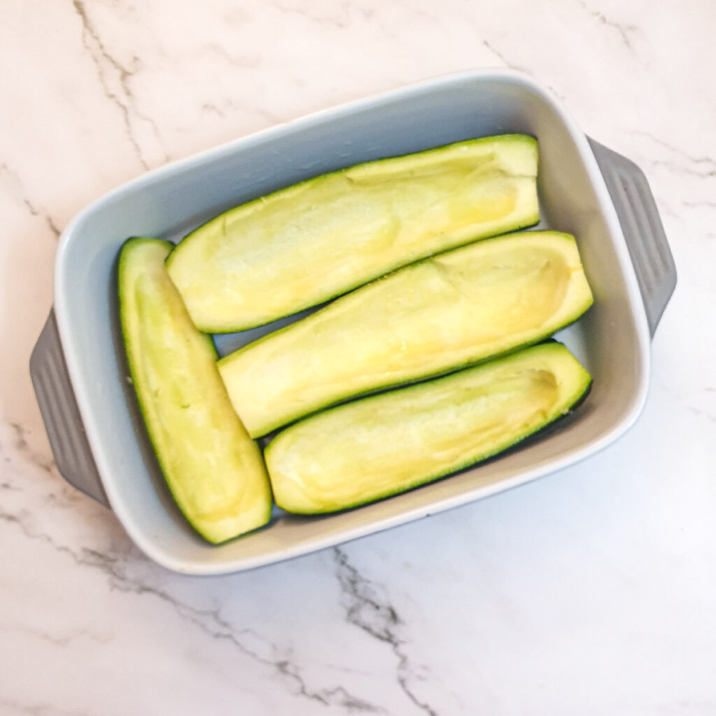 4 hollowed out courgettes in a baking dish.