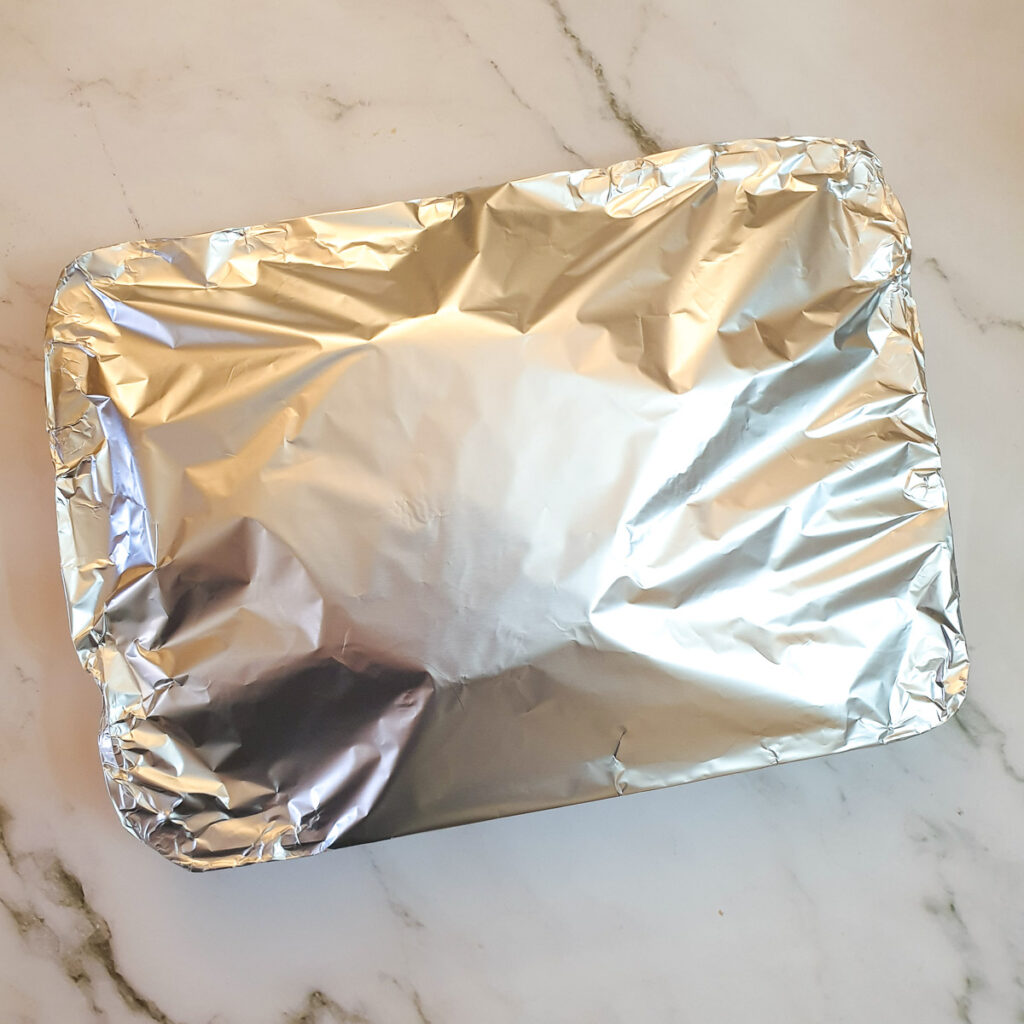 A gammon in a roasting pan covered with tin foil.