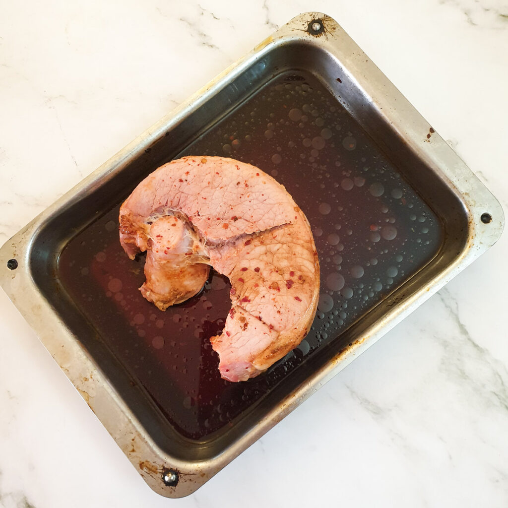 Cooked gammon in a roasting pan.