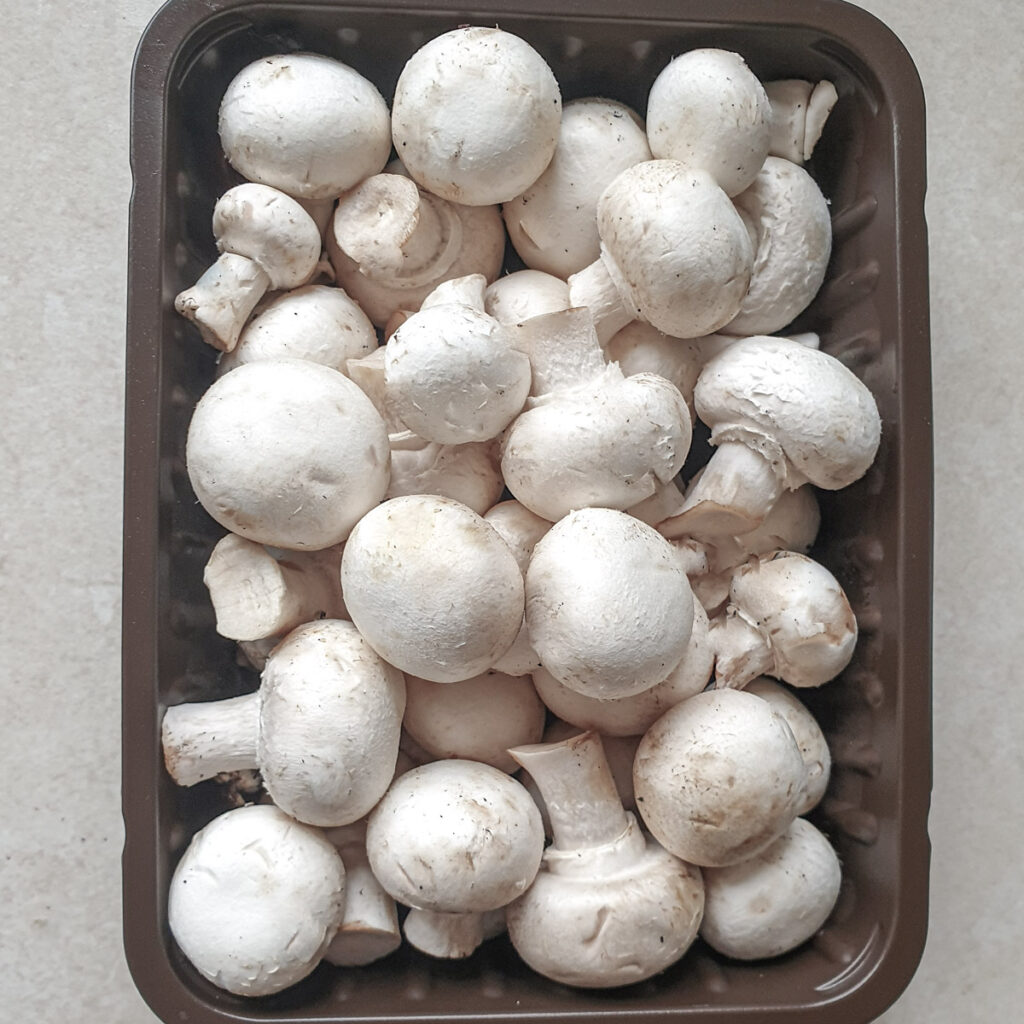 A punnet of white mushrooms.