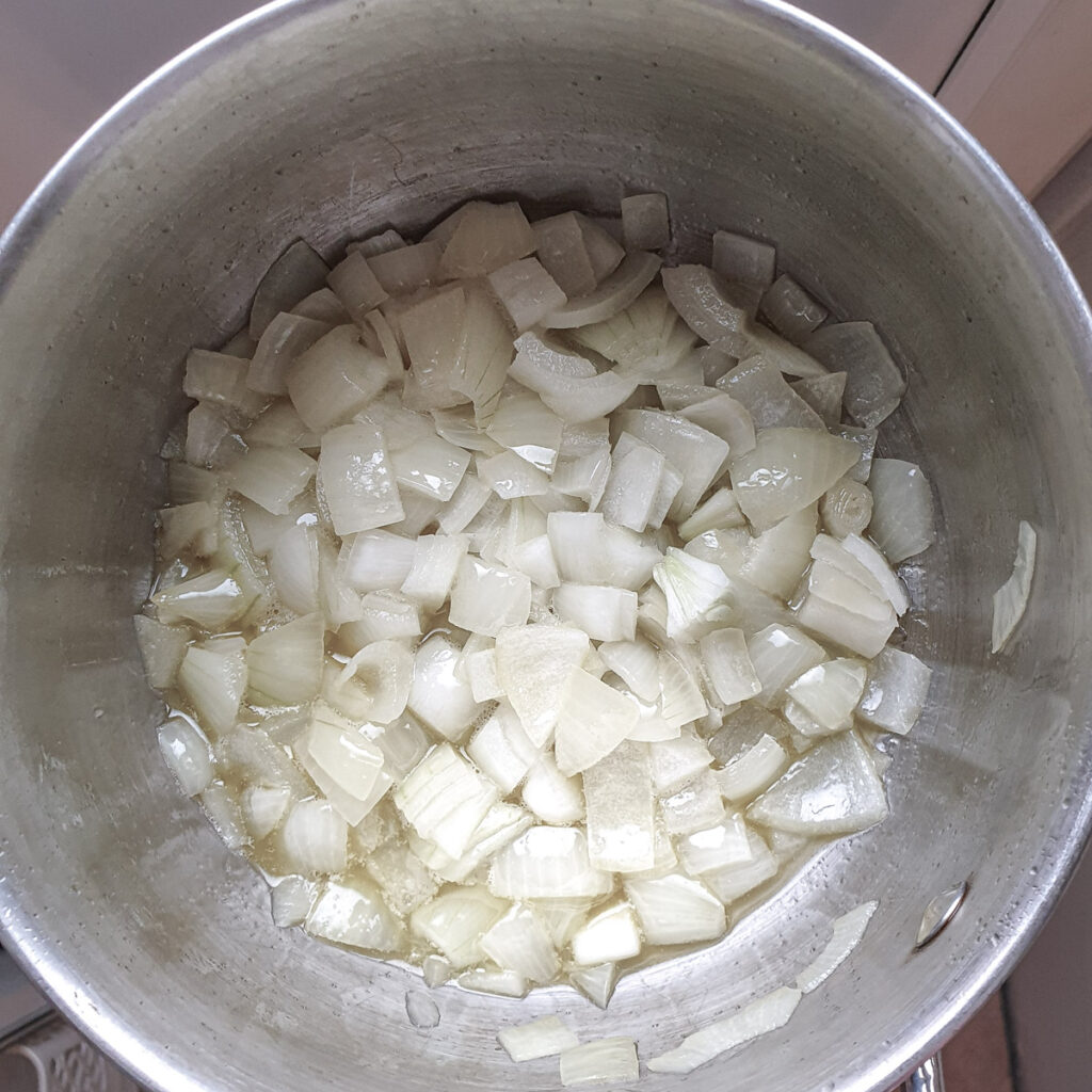 Chopped onions frying in butter in a saucepan.