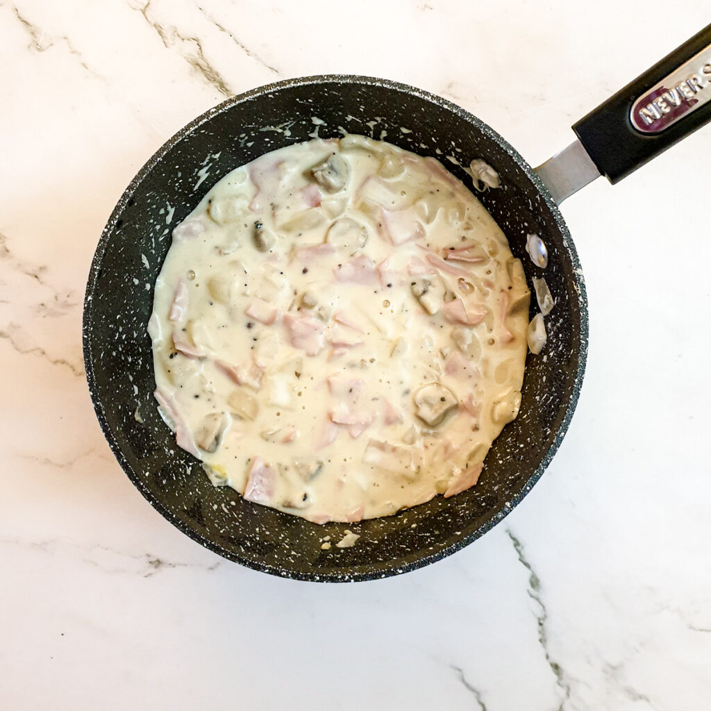 Ham and mushroom sauce in a saucepan.