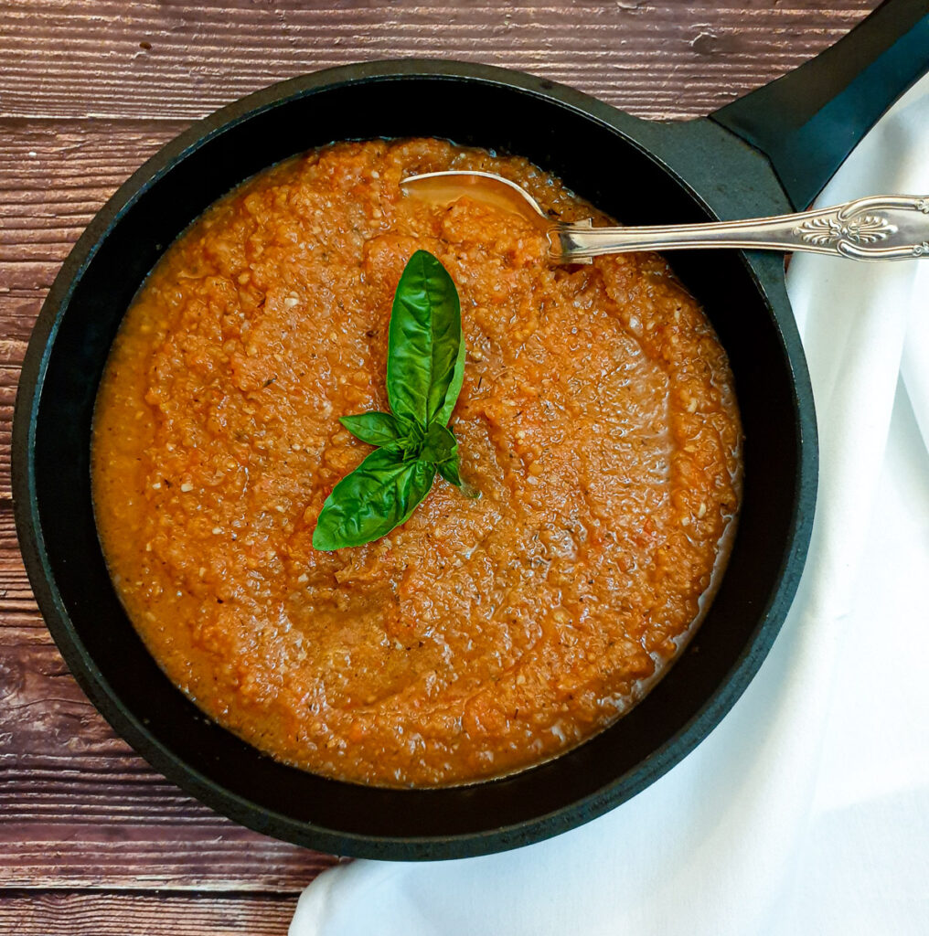 Marinara sauce garnished with basil in a frying pan.