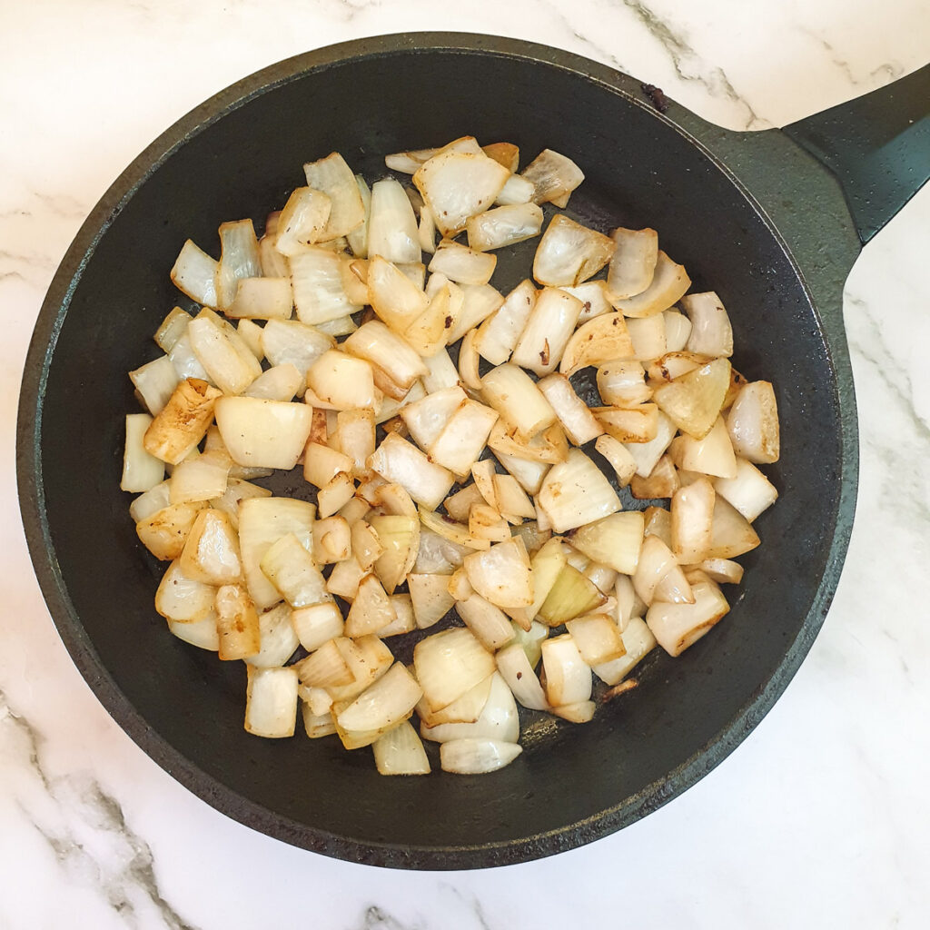 Diced onions frying in a frying pan.