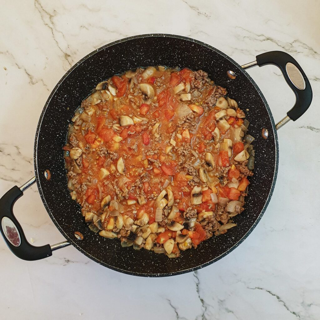 Tomatoes and onions softening with mince and onions.