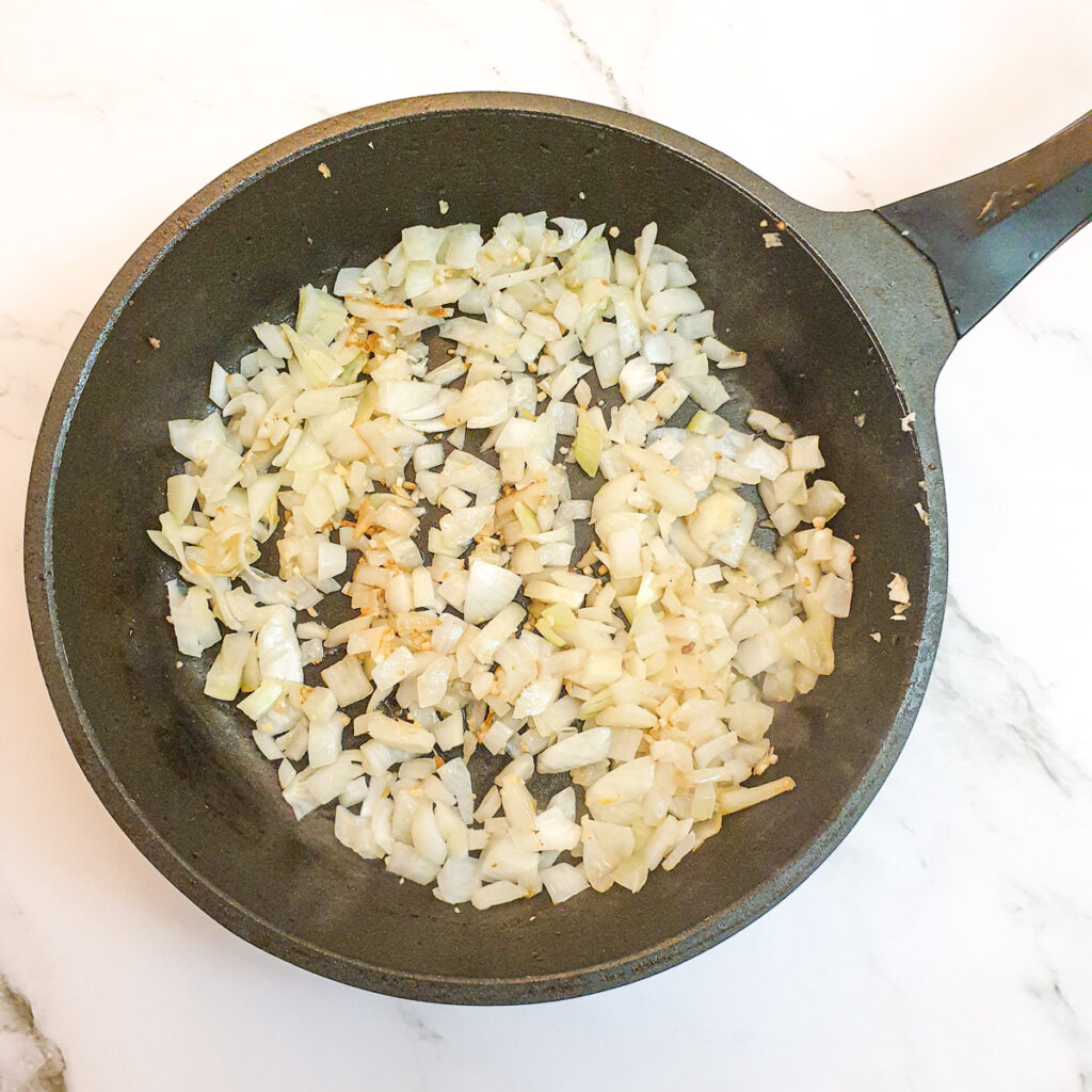Finely chopped onions frying in a pan.