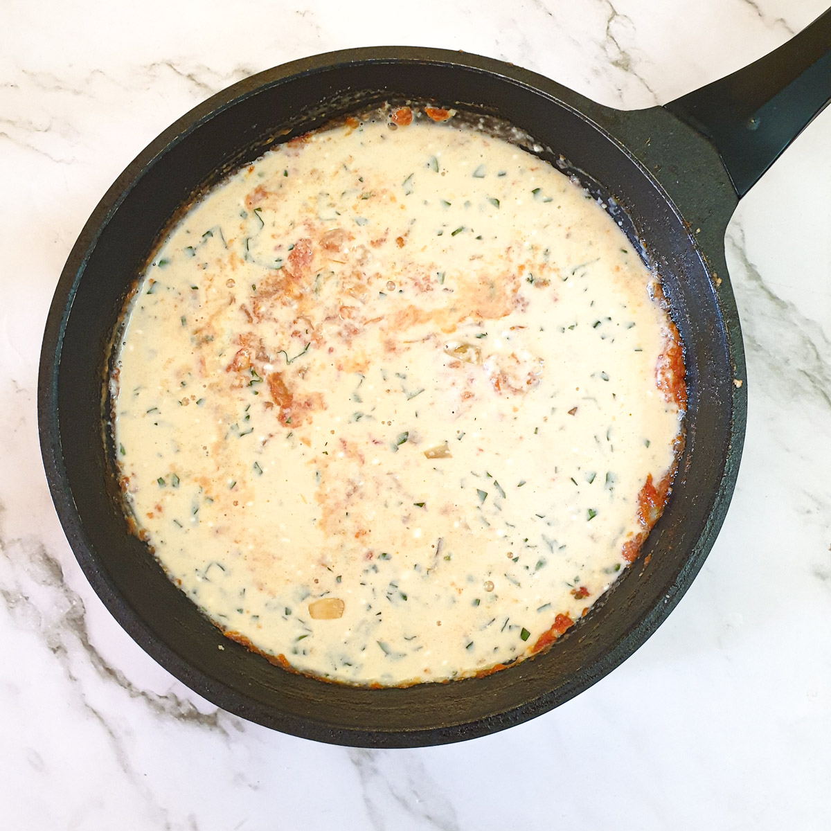 Egg custard mixture mixed with cooked onions and tomatoes in a frying pan.