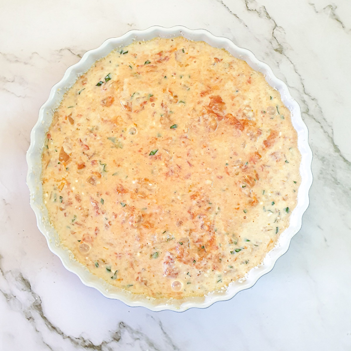 Filling for crustless tomato quiche in a baking dish.