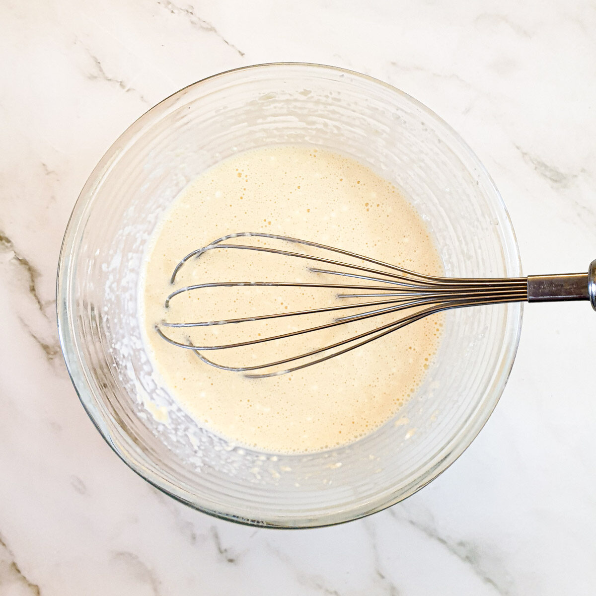 Egg custard ingredients whisked together in a mixing bowl.