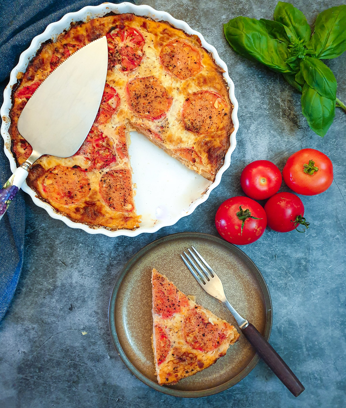 Overhead shot of a tomato and onion quiche with a slice removed onto a plate.