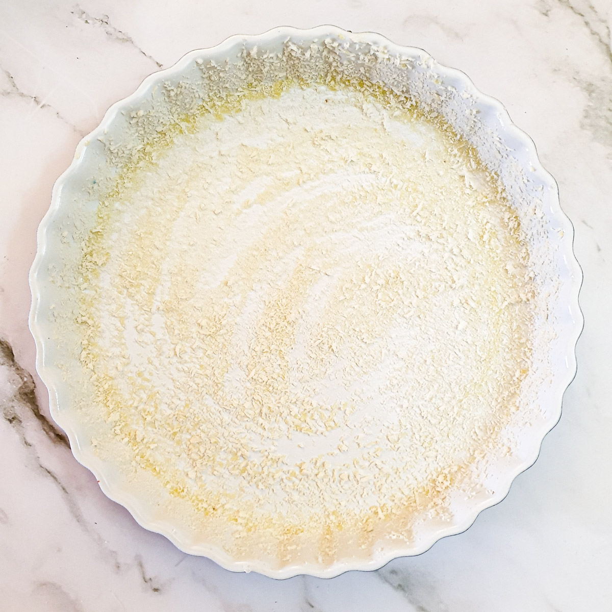 A round baking dish coated with oil and breadcrumbs.