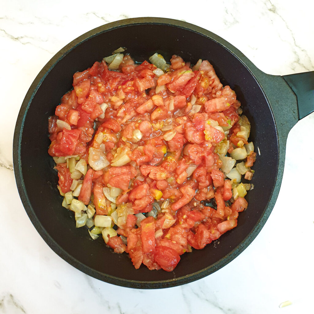 Diced tomatoes and onions in a frying pan.