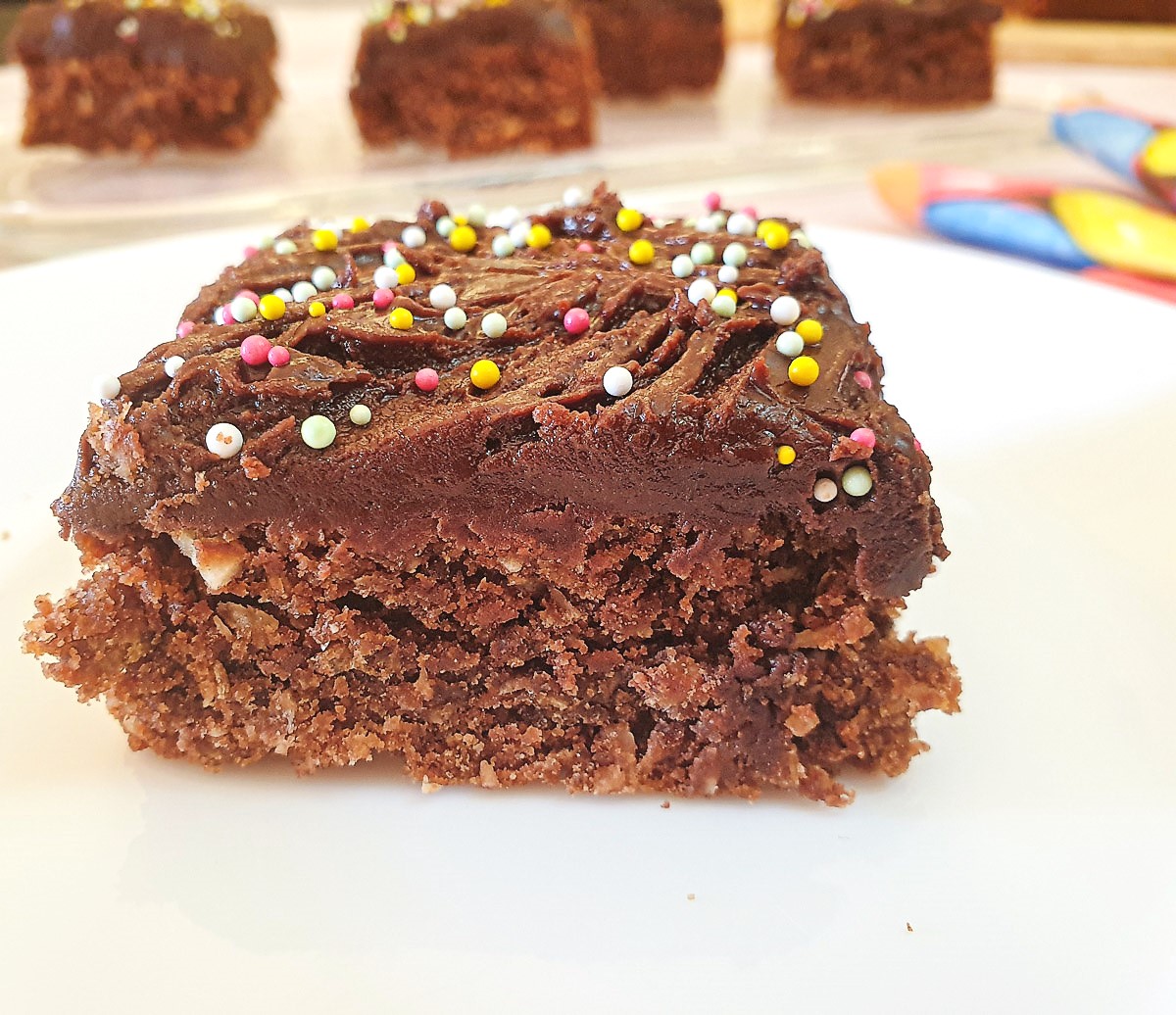 Close up of chocolate weetbix crumble cake with more slices out of focus in the background.