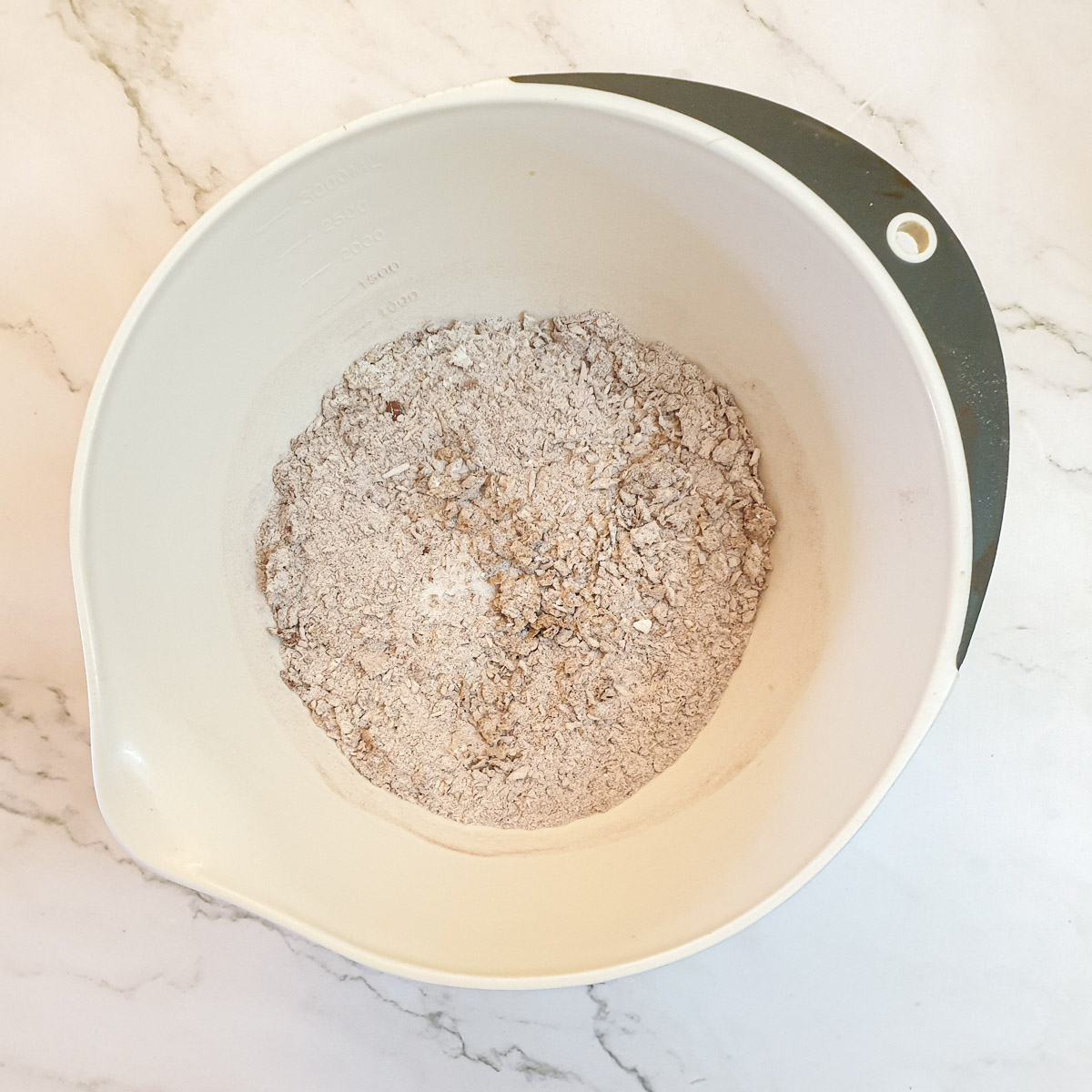 Flour, butter, cocoa and coconut combined in a mixing bowl.