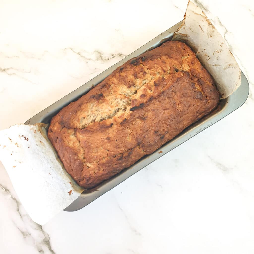 A baked pear and banana loaf in a baking tin.