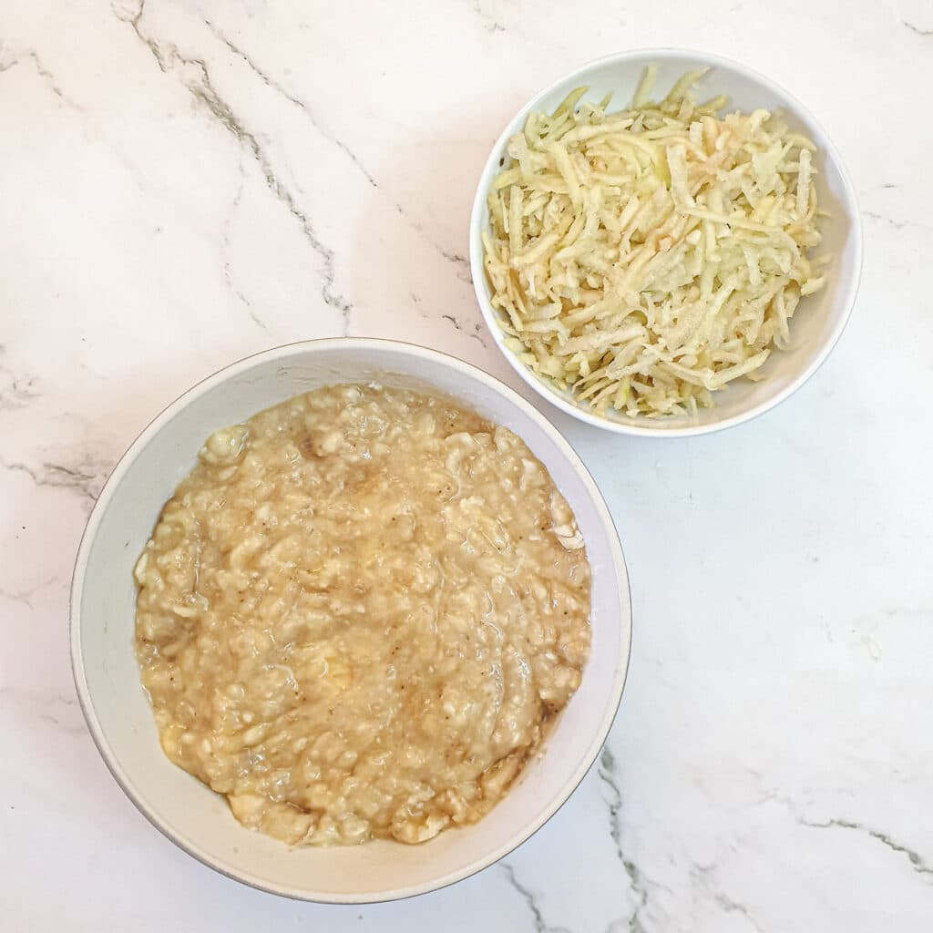 Mashed bananas and grated pears in bowls.