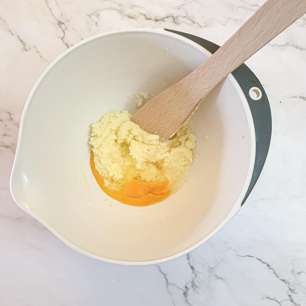 Creamed butter and sugar with an egg in a mixing bowl.