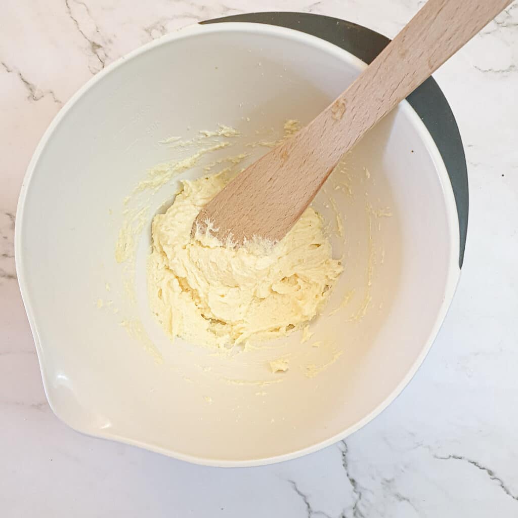 Butter and sugar creamed together with an egg in a mixing bowl.