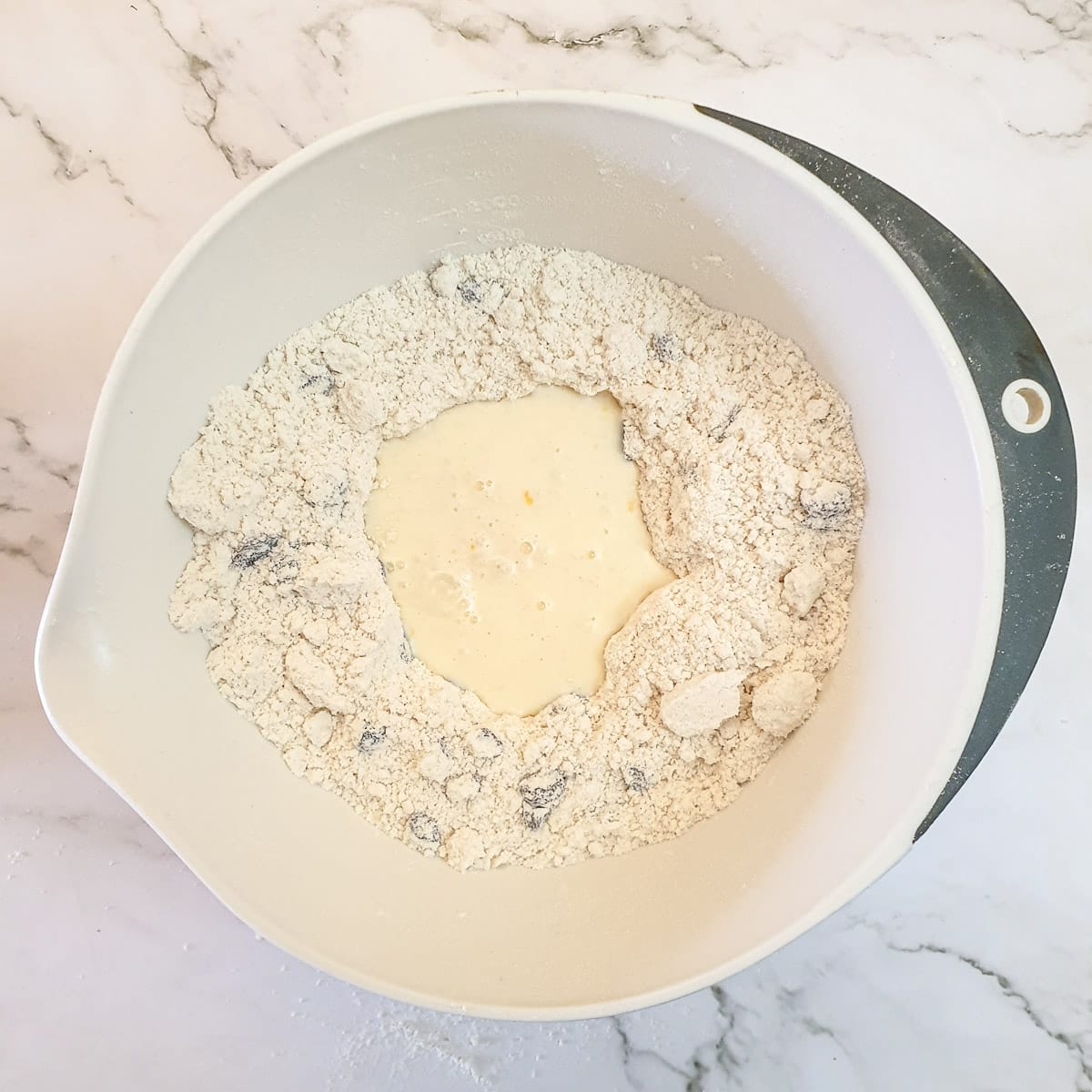 Egg and milk in a mixing bowl with flour mixture.