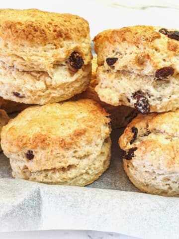 A pile of sultana scones on a baking tray.