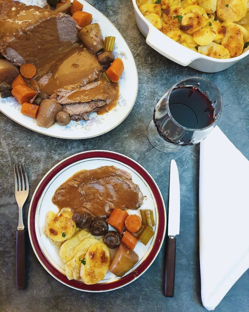 Overhead shot of a plate of sliced beef and vegetables on a table.